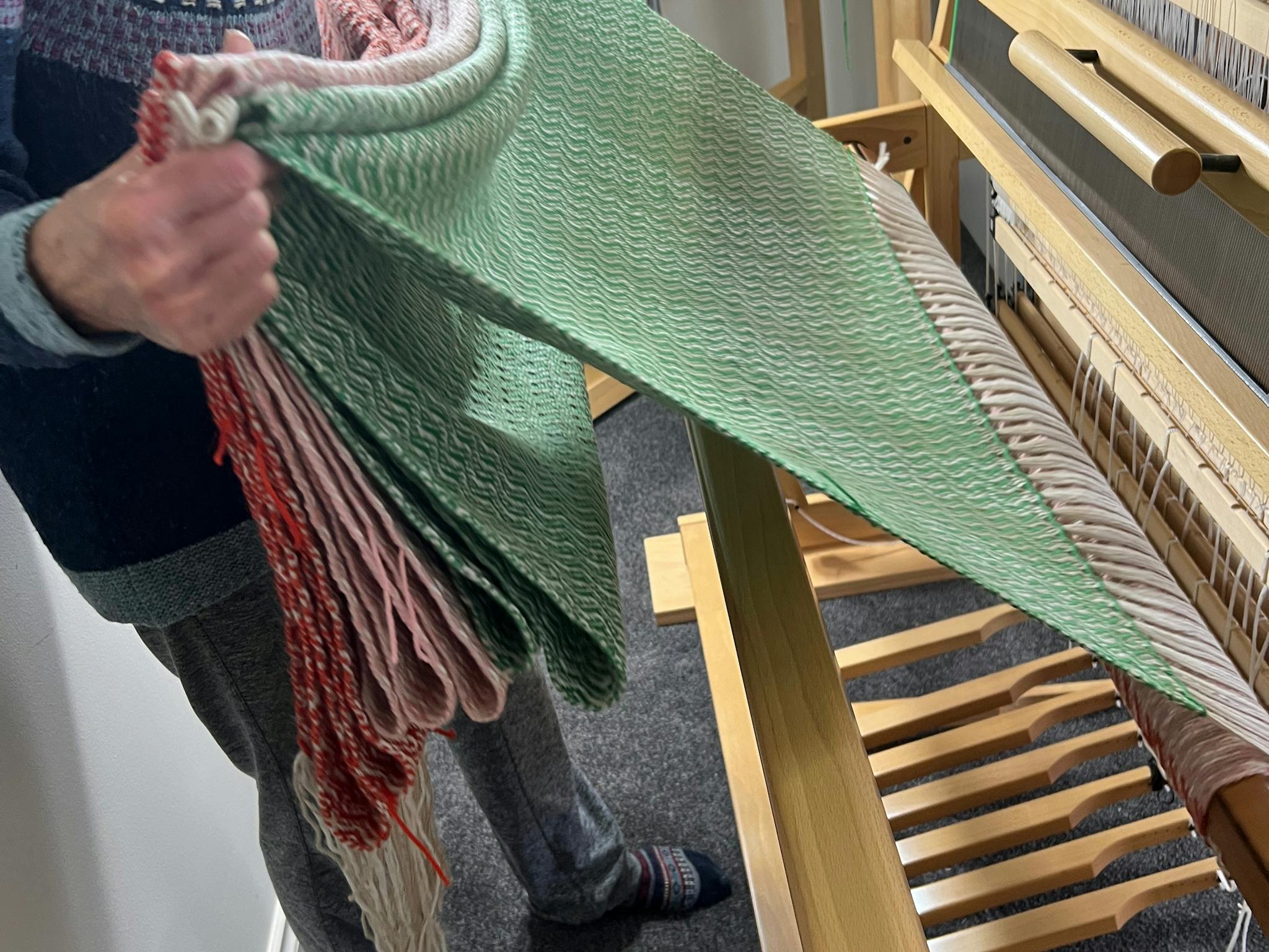 textile is removed from a loom after hours of assembly and weaving