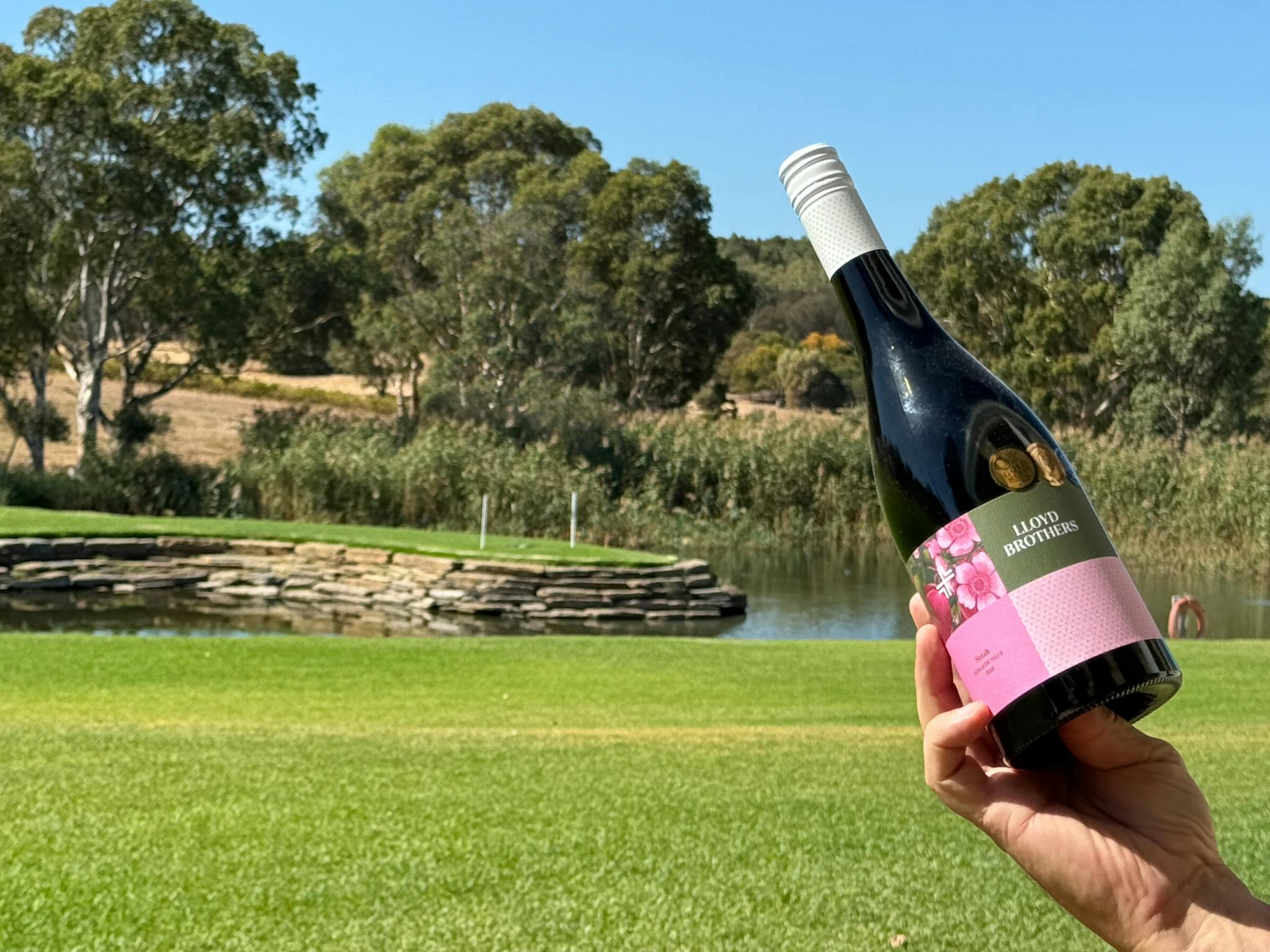 A bottle of Syrah, with the picturesque grounds of Lloyd Brothers Wines, McLaren Vale  beyond