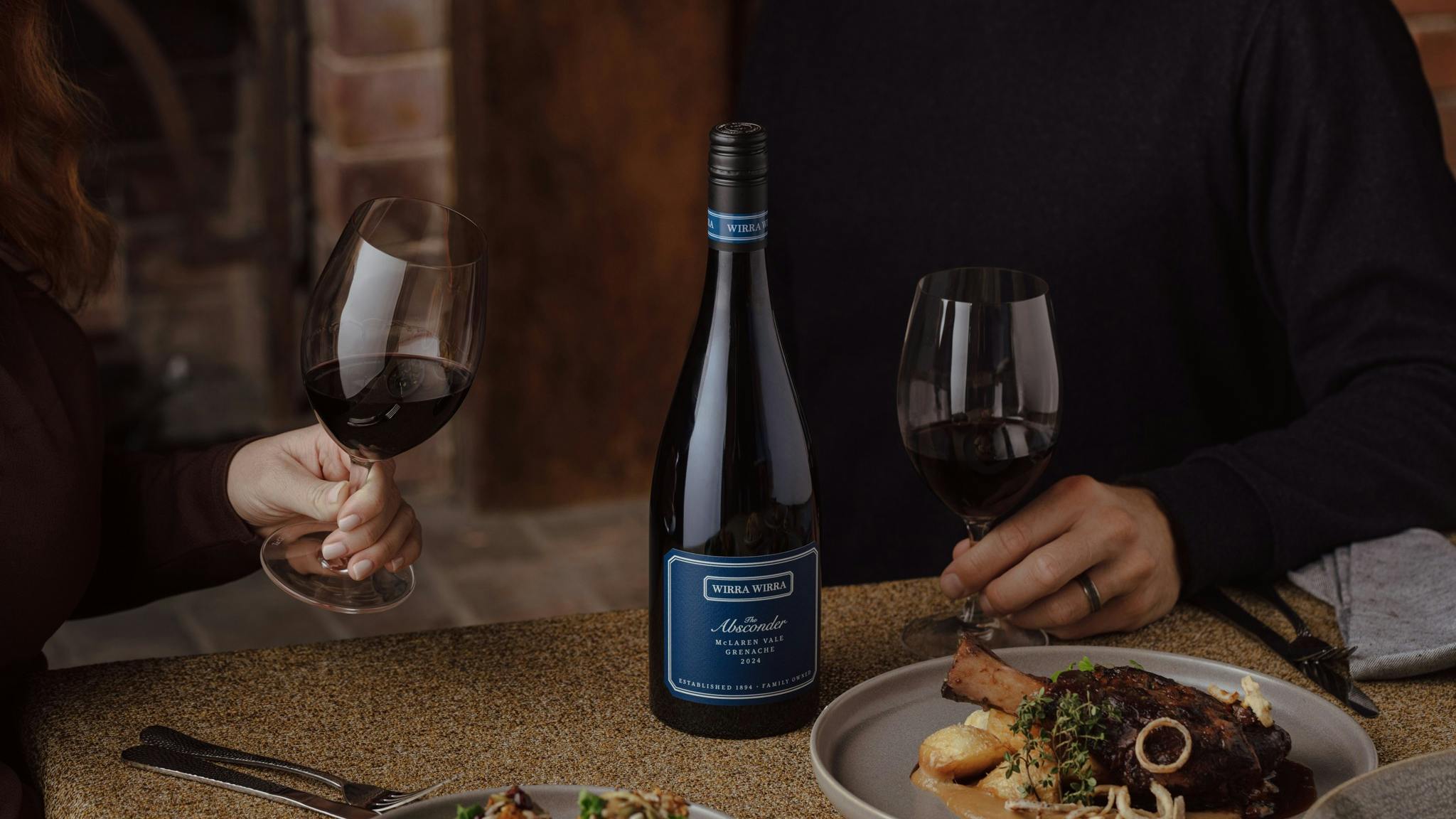 A couple at a table with a bottle of The Absconder Grenache