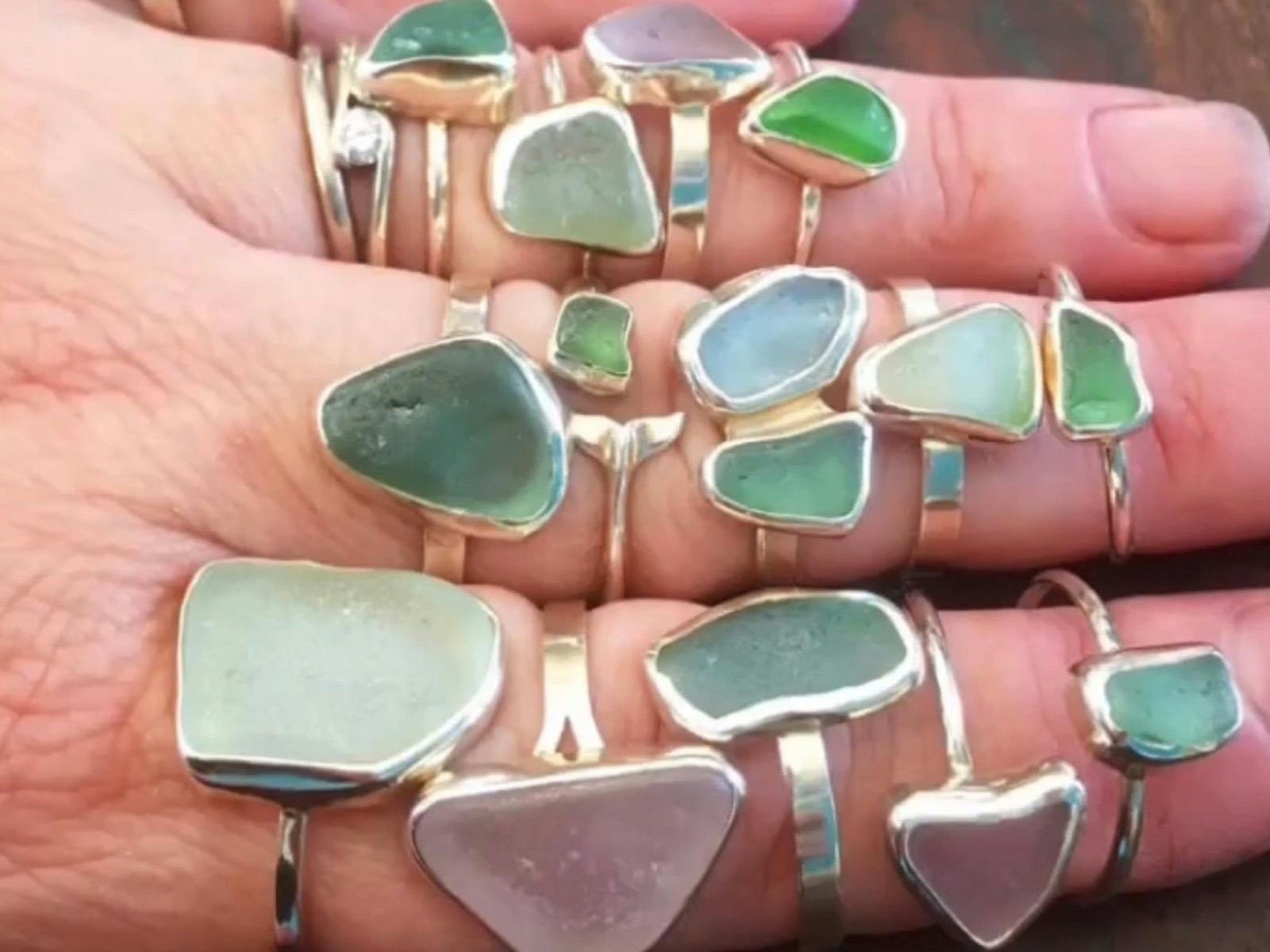 a hand with lots of silver rings made with sea glass