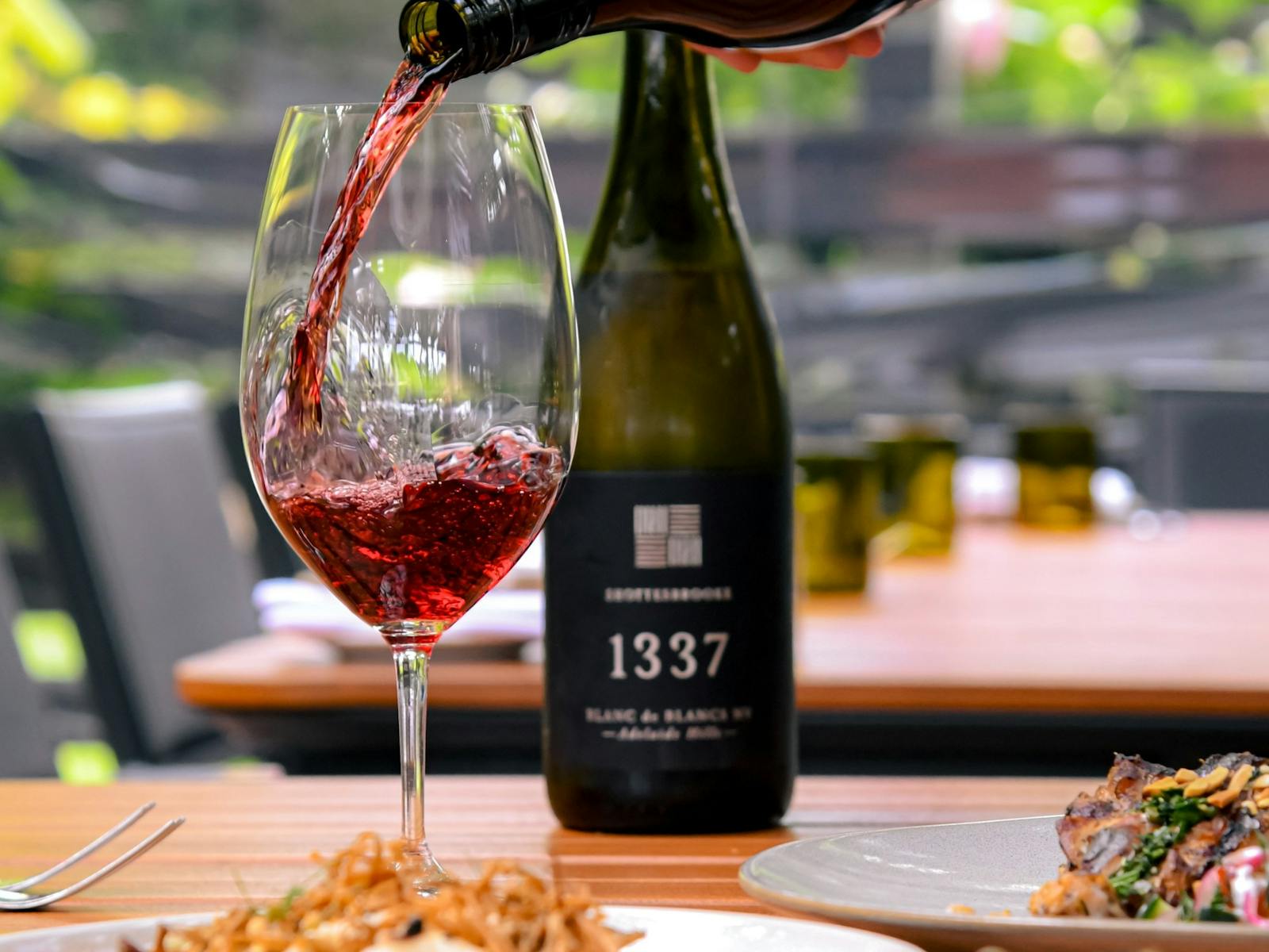 Red wine being poured into glass with bottle in background