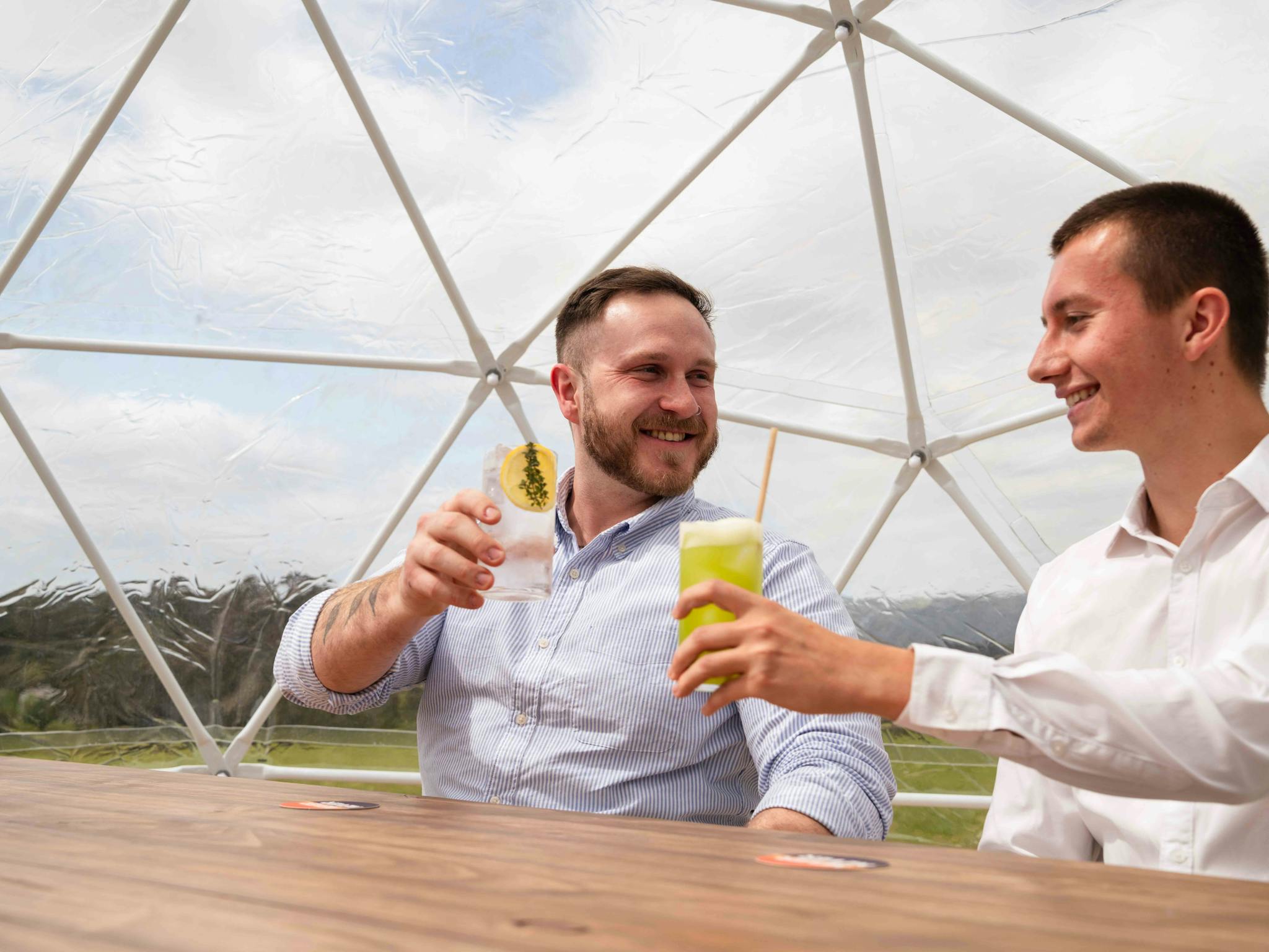 two men cheersing gin glasses with smiles