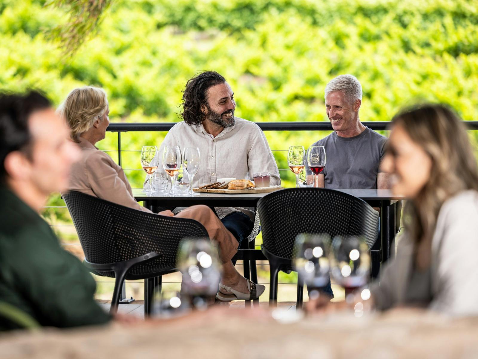 Guests seated at table for wine tasting in front of vineyards