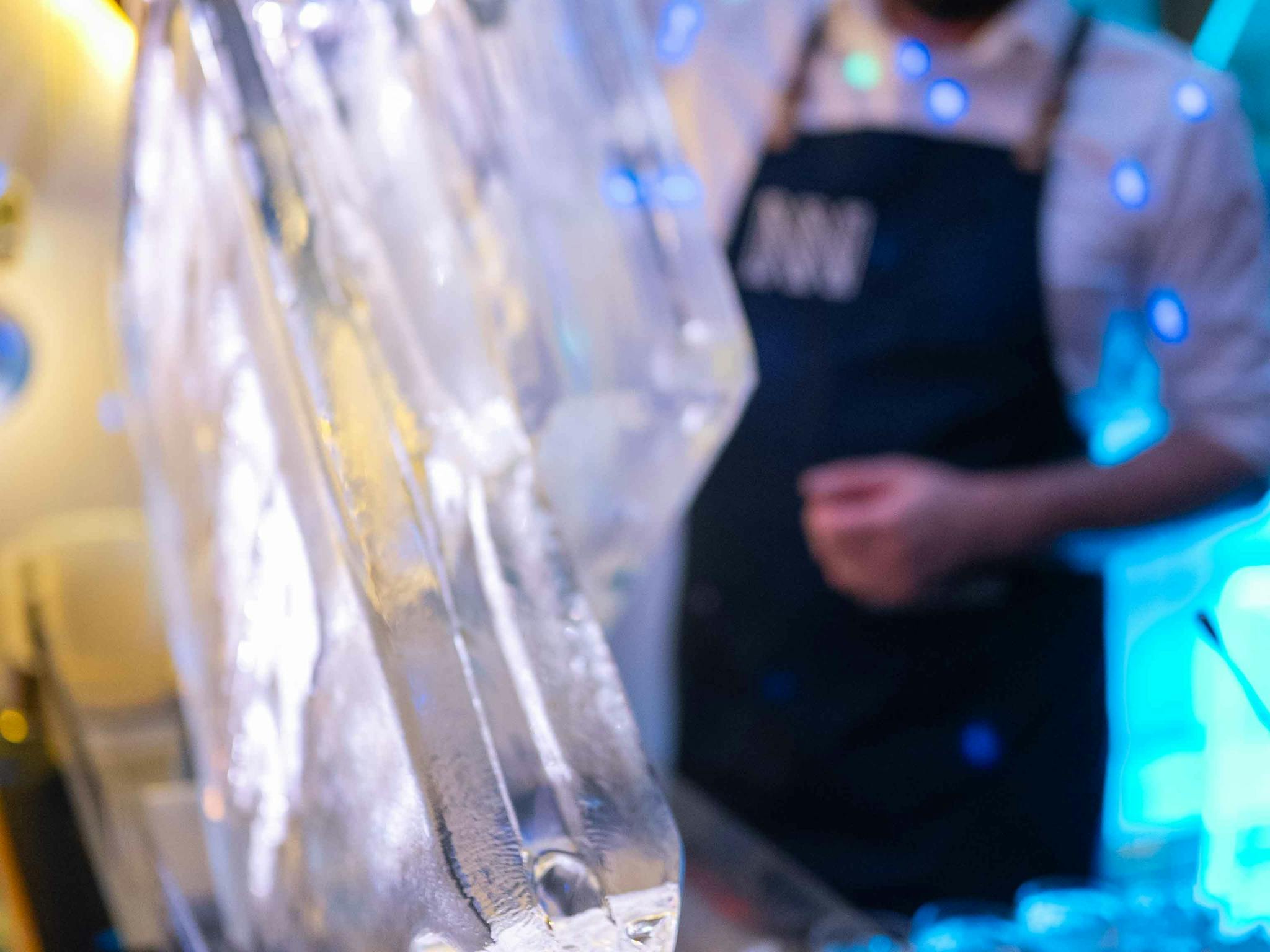 A bartender pours a martini serve down the ice luge into a mini martini glass