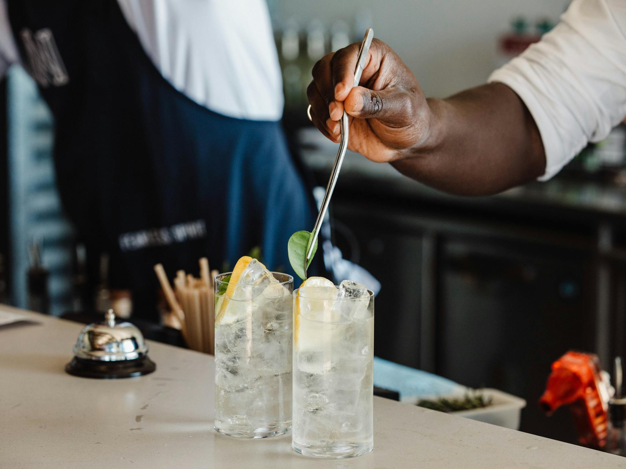 Bartender putting garnish into gin and tonic