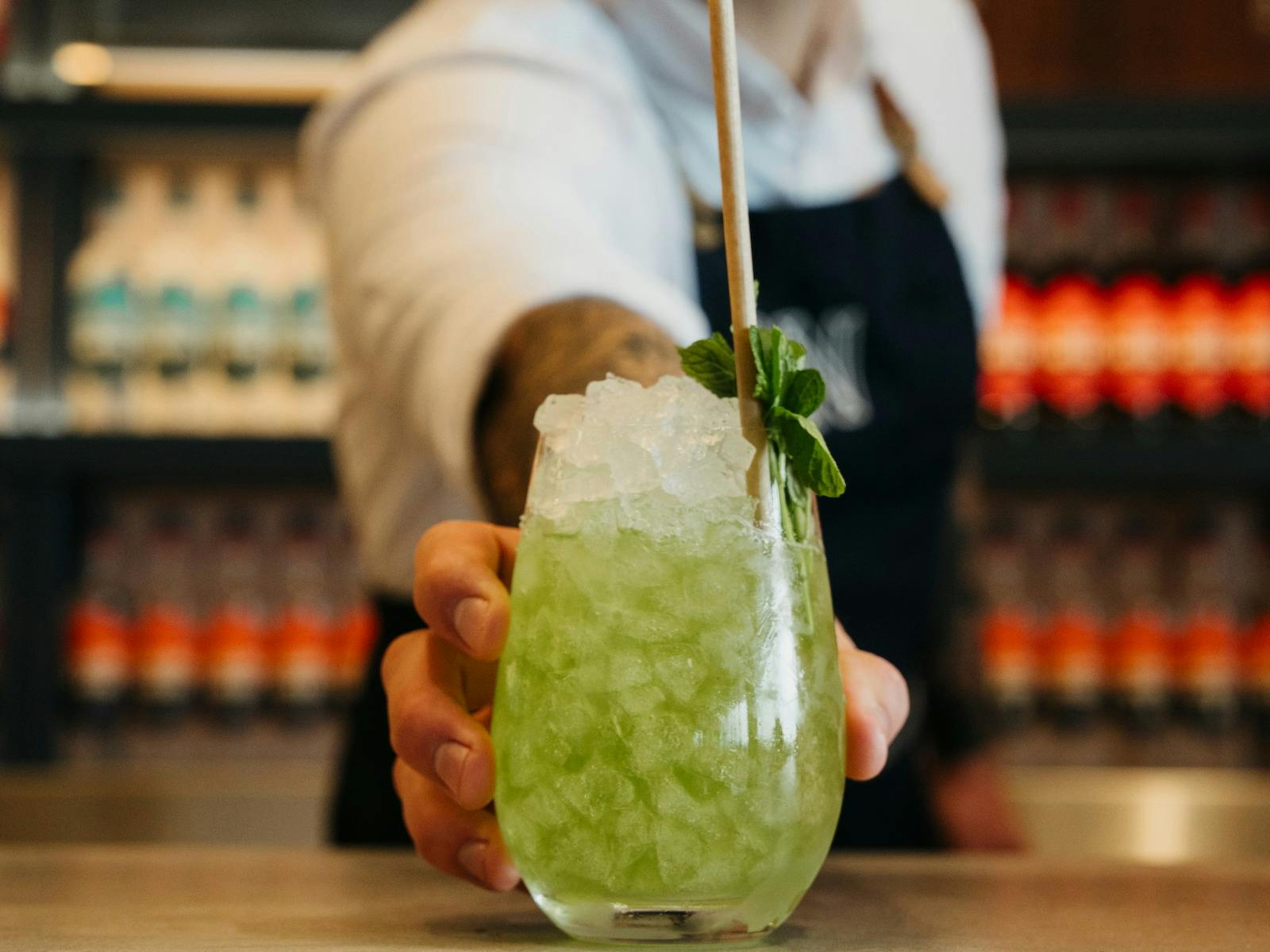 green cocktail served on crushed ice with mint sprig and straw