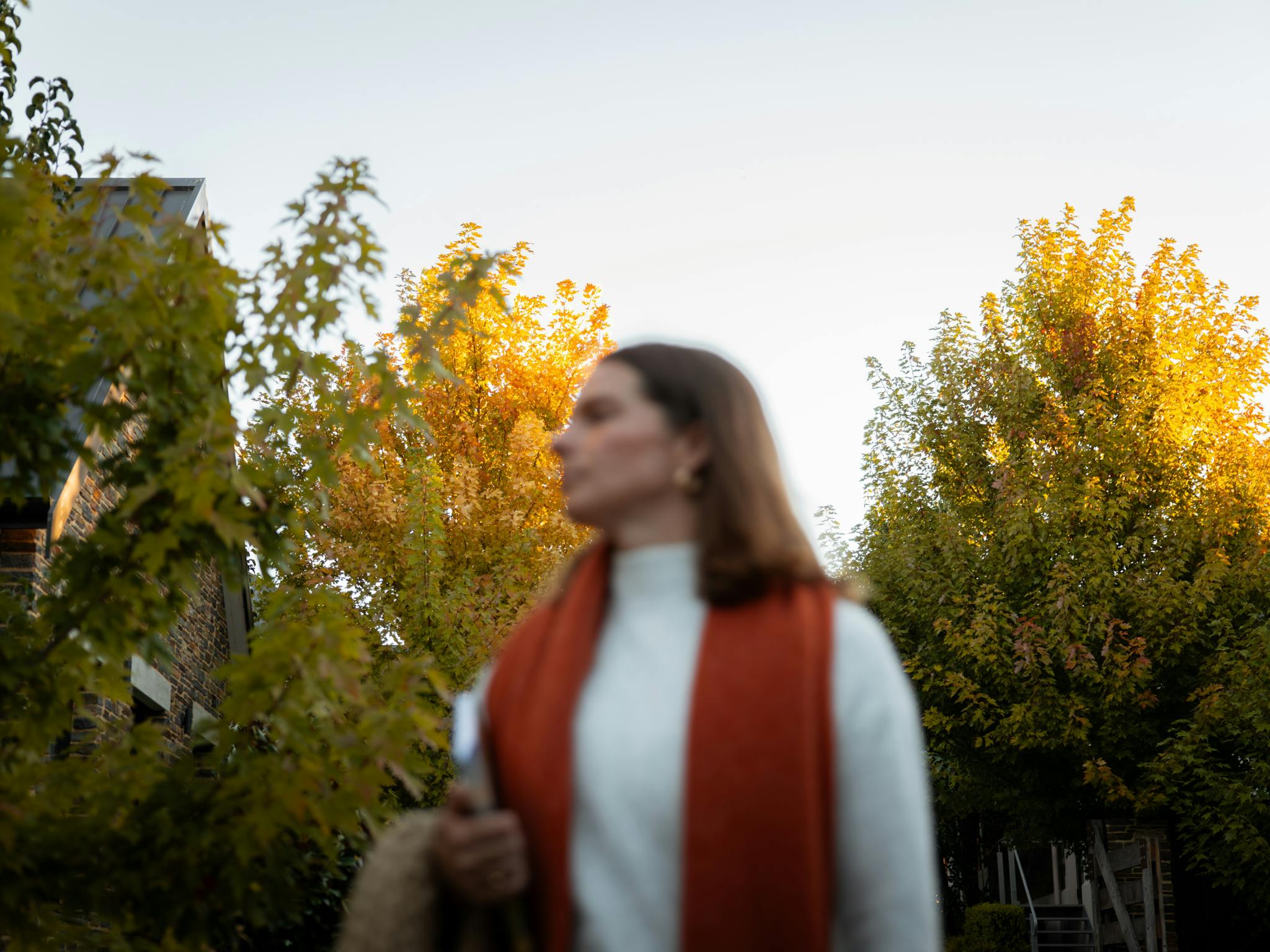 Woman walking down a driveway at Vale 194 in McLaren Vale with glowing autumn trees in the backgroun