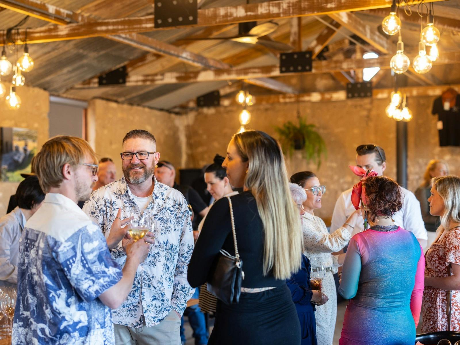 Guests male and female enjoying a party held at the Varney Wines Tasting Room heritage barn.